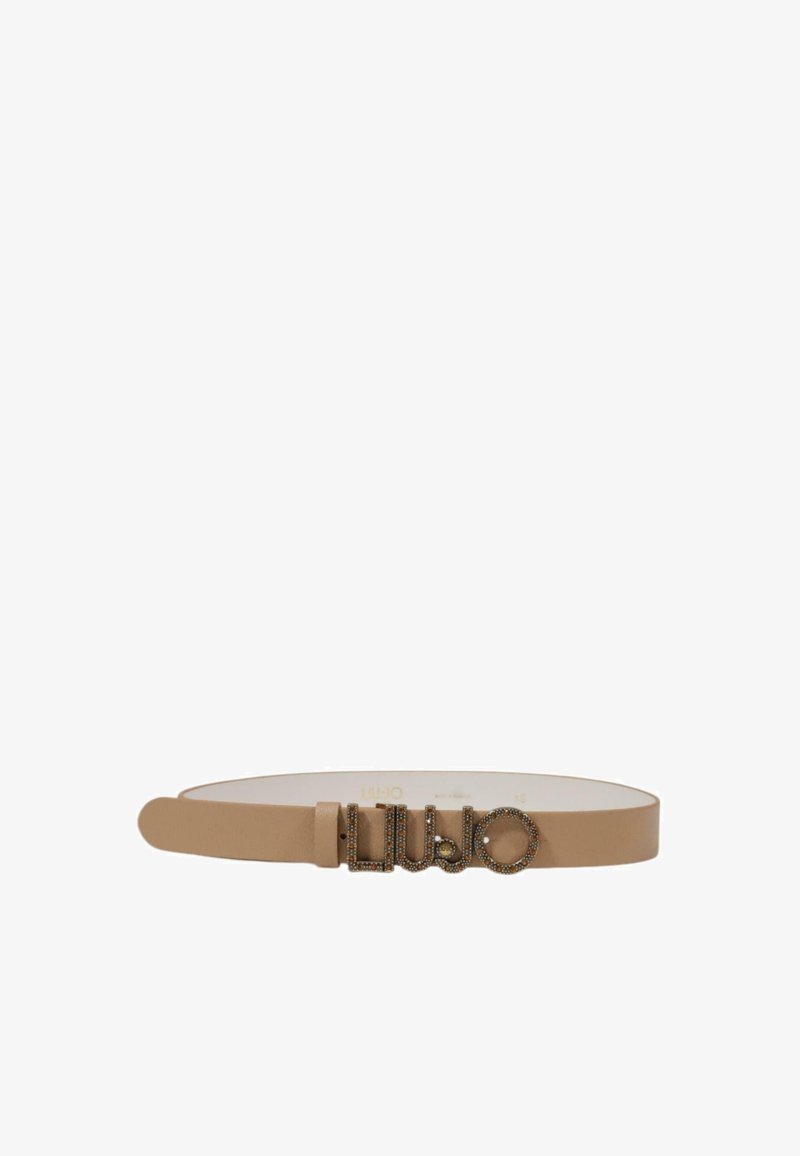 Bež usnjen pas z gladko teksturo, ki ima kovinski logotip z dekorativnimi kamni in je pritrjen s preprosto zaponko.