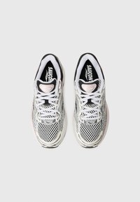 White and black mesh running shoes with pink accents, featuring a rounded toe, lace-up design, and rubber sole. Logo visible on the tongue.