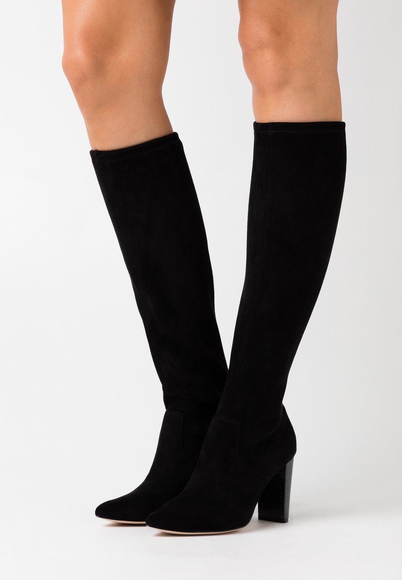 Botas altas de ante negras hasta la rodilla con punta afilada y tacón ancho, que presentan una textura suave y un diseño sin costuras.