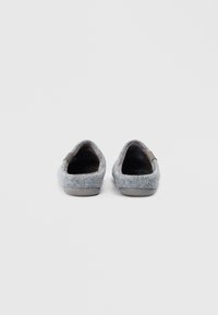 Chinelos cinzentos com uma textura suave, forma arredondada e um design minimalista. Inclui um discretamente cinza acento no calcanhar.