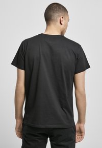 Black short-sleeve t-shirt made of cotton with a round neckline. Simple design, smooth texture, and straight hem at the waist.