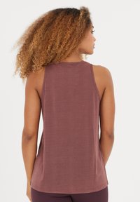 Top sin mangas color marrón con un corte relajado, textura suave y un dobladillo redondeado. Presenta una amplia sisa y un diseño simple sin adornos.