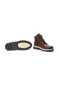 Botas de senderismo de cuero marrón con un cuello acolchado, cierre de cordones en la parte delantera y cremalleras laterales. Cuentan con una suela de goma negra resistente con un relieve texturizado.