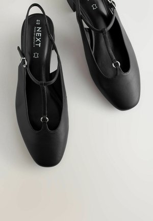 Čierne topánky so zadným pásikom, ktoré majú hladký kožený zvršok, dizajn T-pásika, okrúhlu špičku a nízky blokový podpätok so striebornými kovovými detailmi.