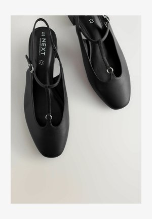 Čierne topánky so zadným pásikom, ktoré majú hladký kožený zvršok, dizajn T-pásika, okrúhlu špičku a nízky blokový podpätok so striebornými kovovými detailmi.