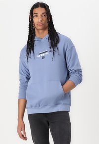 Light blue cotton hoodie with a kangaroo pocket and drawstring hood, featuring a graphic text print on the chest and ribbed cuffs.