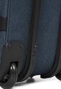 Blue fabric suitcase featuring black plastic corners and wheels, textured surface, and a compact design with a single carry handle.