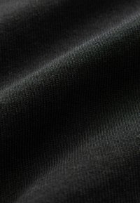 Sort ribbet stof med en blød tekstur, der viser tydelige lodrette mønstre. Materialet virker let og let elastisk.