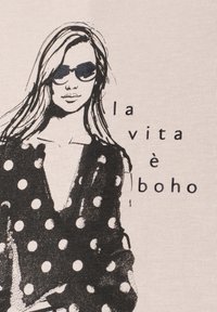 Woman with long hair wearing sunglasses and a polka dot dress, next to the text "la vita è boho" on a light background.