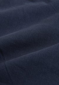 Close-up of dark navy blue fabric with fine ribbed texture and soft folds.