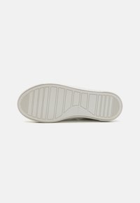 Gummisåle til sneakers, teksturert med parallelle riller og sirkulære mønstre, i solid hvit med svak merkevare nær hælen.