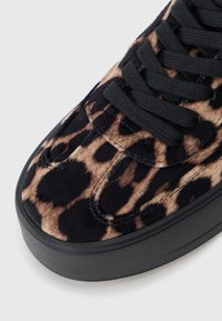 Baskets en suede imprimé léopard avec lacets noirs et semelle en caoutchouc texturé noire. Présente un bout arrondi et des détails cousus.