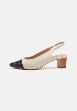 Slingback pump with a white leather upper and a black patent leather toe cap. Features a stacked wooden heel and smooth inner lining.