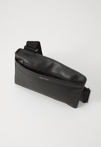 Black leather crossbody bag with a smooth texture, slim rectangular shape, adjustable strap, and a zippered main compartment.
