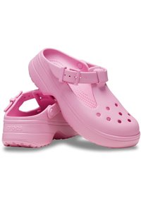 Roze rubberen klompen met een verhoogde band, ventilatiegaten en een textuur in de voetbed. De zool heeft een patroon voor grip en traction.