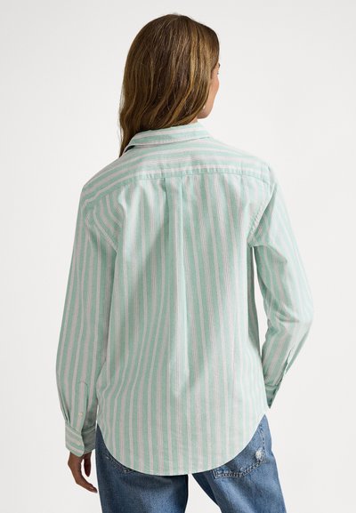 Gaiši zaļa krekls ar baltām un rozā vertikālām svītrām, garām piedurknēm, pogājamu apkakli un izliekta apakšdaļa. Skats no aizpuses rāda kopējo piegulumu.