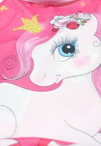 Maillot de bain pour enfant avec une licorne rose aux yeux bleus, ornée de roses et d'une couronne dorée sur un fond rose clair.