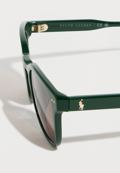 Σκούρα πράσινα ορθογώνια γυαλιά ηλίου με σκούρους φακούς και ένα μικρό χρυσό λογότυπο παίκτη πόλο στον βραχίονα του πλαισίου.