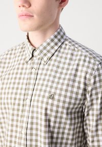 Camicia a quadri verde e bianca con colletto a punta, caratterizzata da un piccolo logo sul petto e tessuto testurizzato.