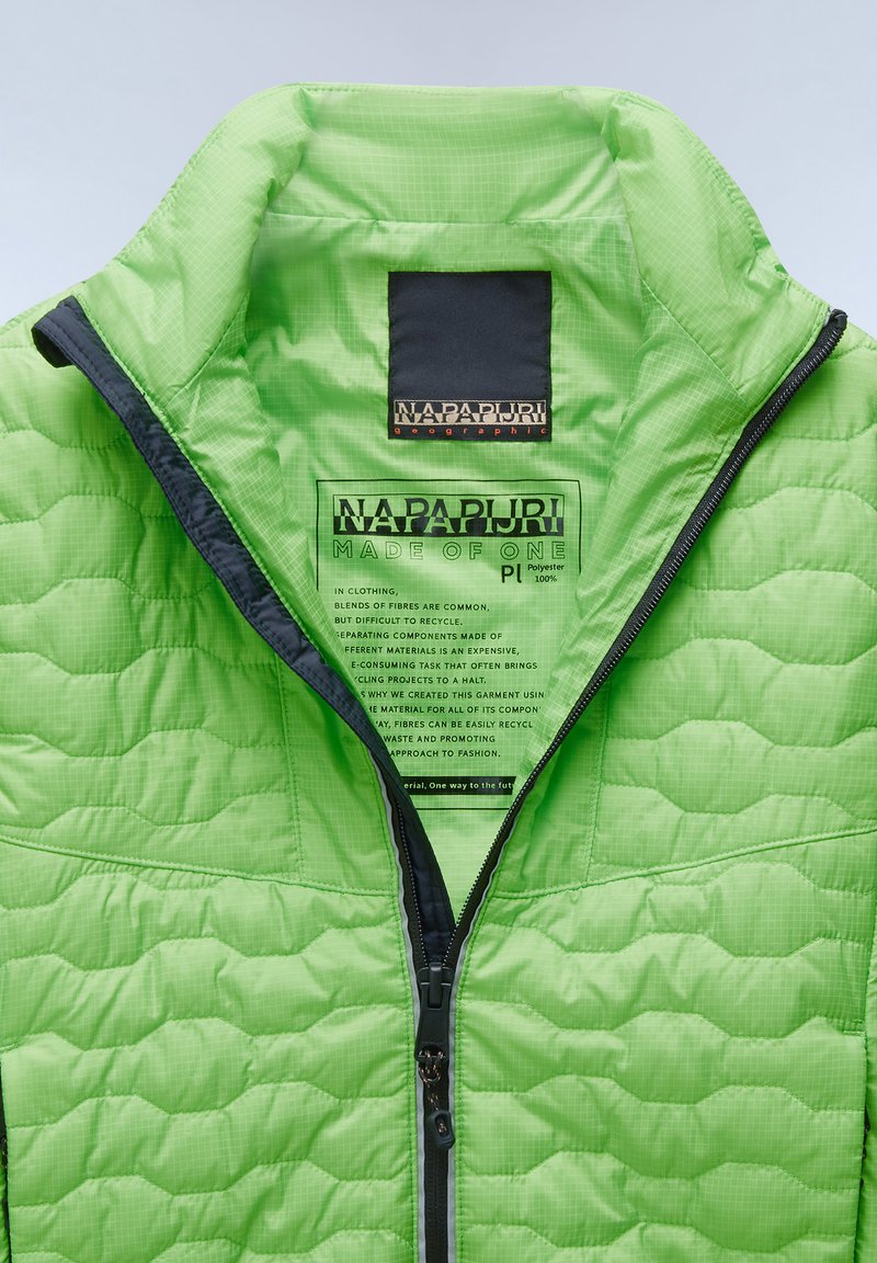 Chaqueta acolchada verde con un alto cuello, cremallera negra y etiqueta interior que detalla la composición del tejido y las instrucciones de cuidado.