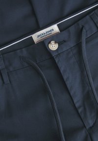 Pantaloni blu navy con chiusura a bottone, cordoncino elastico e etichetta con il logo Jack & Jones. Tessuto liscio, senza motivi.