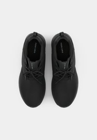 Zwarte sportieve schoenen met een gladde textuur, ronde neus en vetersluiting. Versterkt met een lus bij de hiel en een logo op de tong.