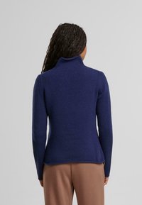 Navyblaue Rollkragenpulli mit gerippter Textur, enganliegendem Schnitt, langen Ärmeln und einem leicht ausgestellt geschnittenen Saum.