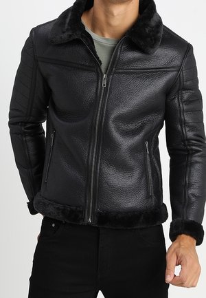 Schwarze Lederjacke mit strukturierter Oberfläche, ausgestattet mit einem Kunstfellkragen und -bündchen, Reißverschlusstaschen und gesteppten Details an den Ärmeln.