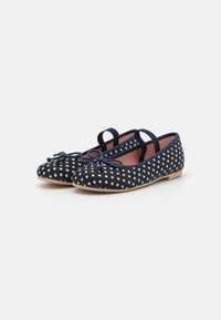Ballerine in tela blu con pois bianchi, caratterizzate da un dettaglio a fiocco, suola piatta e cinturini elastici per una vestibilità sicura.