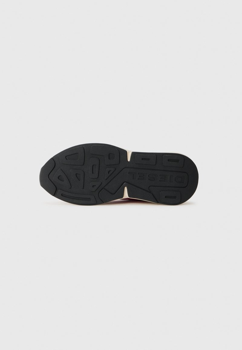 Semelle de sneaker noire en caoutchouc avec motifs de texture et détail de logo. Présente une forme courbée et une semelle intermédiaire de couleur crème contrastante.