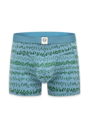 Boxer bleu clair avec des motifs d'arbres verts et une petite étiquette blanche avec un logo visage d'ours sur la ceinture.