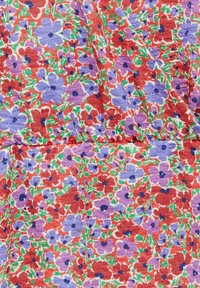 Tissu floral avec un fond rouge orné de fleurs violettes et rouges ainsi que de feuilles vertes. La texture semble froissée ou texturée.