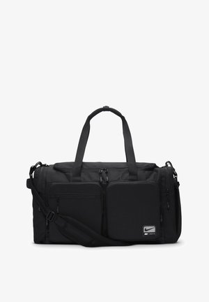 Mala de transporte preta com alças duplas superiores e faixa de ombro ajustável, apresentando vários bolsos com fecho e um emblema da Nike.