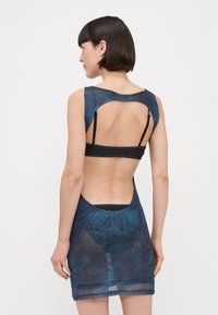 Vestido de malla azul con una forma ajustada, diseño de espalda descubierta y acentos negros. Presenta contornos cosidos y un patrón de superficie texturizado.