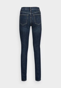 Smala jeans i mörk denim med en slät yta, med en midjehöjd i normal nivå, två bakfickor och en figursydd silhuett.