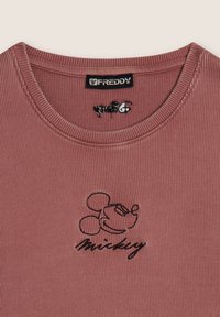 Maglietta in cotone a coste di colore rosa con ricamo nero del personaggio Mickey Mouse e testo in corsivo. Scollatura ampia con cuciture rinforzate.