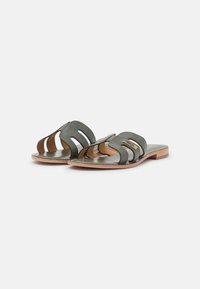 Donkergroene leren sandalen met meerdere uitsnijdingen, platte houten hak en een gladde binnenvoering. Verfraaid met metallic details.