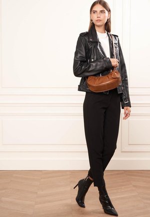 Zwarte leren motorjack, wit shirt, zwarte tailored broek, bruine crossbody tas en zwarte enkellaarsjes met hak en spitse neuzen.