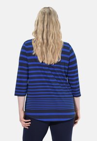 Top a maniche lunghe blu e navy a righe, con orlo arrotondato e maniche a tre quarti, realizzato in un tessuto morbido e elasticizzato.
