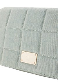 Džínová kabelka v světle modré barvě s prošívaným designem. Obsahuje zlatou logovou destičku a kontrastní švy. Obdélníkový tvar s hladkým povrchem.