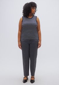 Κορυφή με ρίγες σε ναυτικό μπλε και λευκό, συνδυασμένη με γκρι παντελόνι με ευθεία γραμμή. Μαύρα μπαλαρίνια ολοκληρώνουν την εμφάνιση. Ύφασμα απαλό και εφαρμογή ραμμένη στα μέτρα.