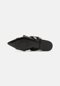 Zapato de tacón alto negro con punta afilada, diseño de tiras y acentos metálicos. Material de cuero liso con un acabado suave y brillante.