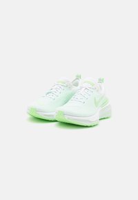 Baskets Nike avec une tige en maille blanche, des accents verts et une semelle en caoutchouc texturé. Comprend un bout rond et un col rembourré pour le confort.