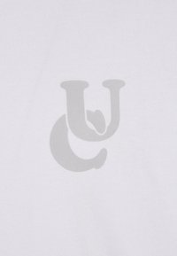 Balts audums izceļas ar lielu, gludu pelēku logotipa dizainu ar stilizētiem burtiem "C" un "U", kas izcelti centrā uz materiāla.