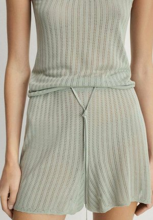 Completo estivo composto da top e pantaloni corti in maglia verde chiaro, caratterizzato da strisce verticali, tessuto testurizzato, vita con cordoncino e orlo a scallop.