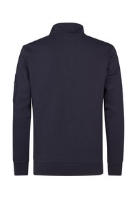 Marineblauwe pullover met een hoge kraag, lange mouwen en geribbelde manchetten. Beschikt over een patchzak op de linker mouw. Zacht, gestructureerd materiaal.