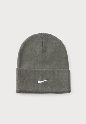 Bonnet en maille gris avec un revers et un logo Nike Swoosh blanc, présenté sur un fond uni.