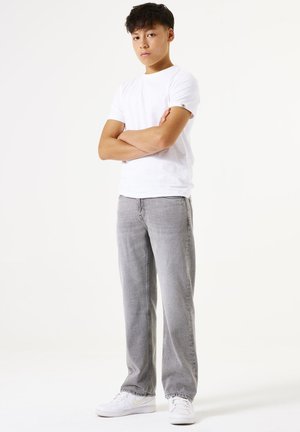 Witte korte mouwen t-shirt gecombineerd met lichtgrijze rechte jeans en witte sneakers; minimalistisch ontwerp met een relaxte pasvorm en geen zichtbare patronen.
