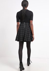Black short-sleeve top paired with a black and white checkered flared skirt, featuring a zipper at the back and opaque black tights.