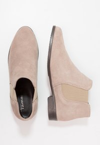 Beige mokkasiner med elastiske sidepaneler, runde tåspisser og lave stablede hæle. Blød tekstur og minimalistisk design.